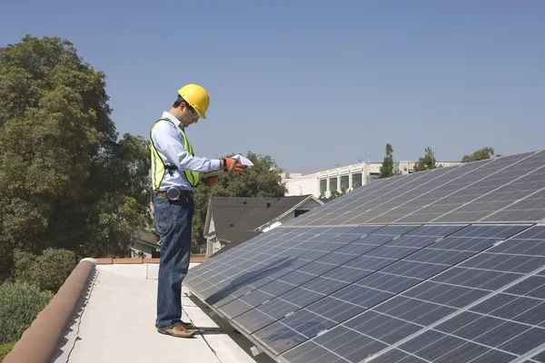 Рабочий обслуживания стоит с солнечной батареей на крыше — стоковое фото