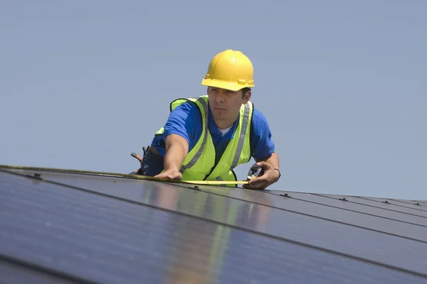Рабочий обслуживания измеряет солнечную батарею на крыше — стоковое фото