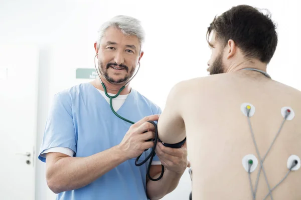 Портрет доктора измерения давления крови пациента в прикроватные — стоковое фото