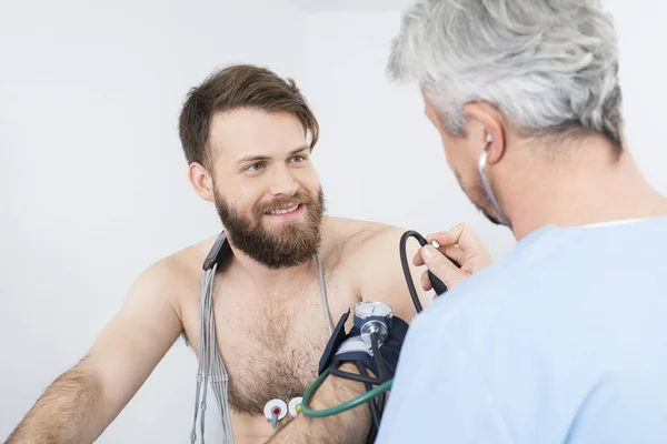 Пациент, глядя на доктор проверку кровяного давления — стоковое фото