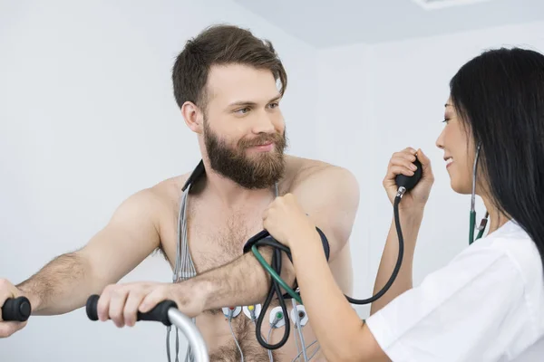 Доктор измерения артериального давления пациента с электродами на бо — стоковое фото