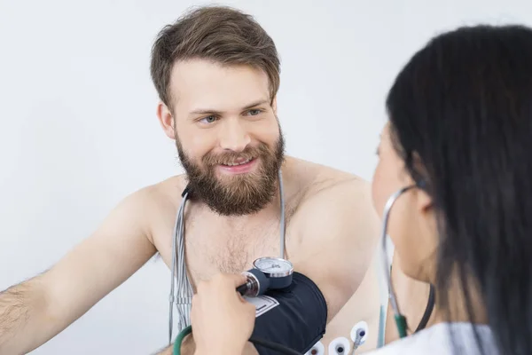 Счастливый пациента, глядя на доктор проверку кровяного давления — стоковое фото