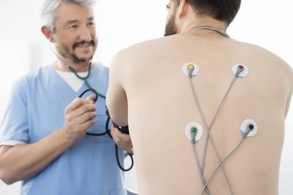 Доктор, изучения пациента с электродами крепится на спине в Hos — стоковое фото