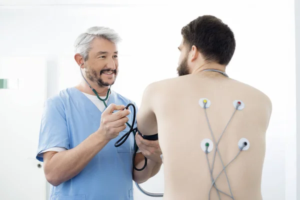 Доктор, изучения пациента с электродами крепится на спине — стоковое фото